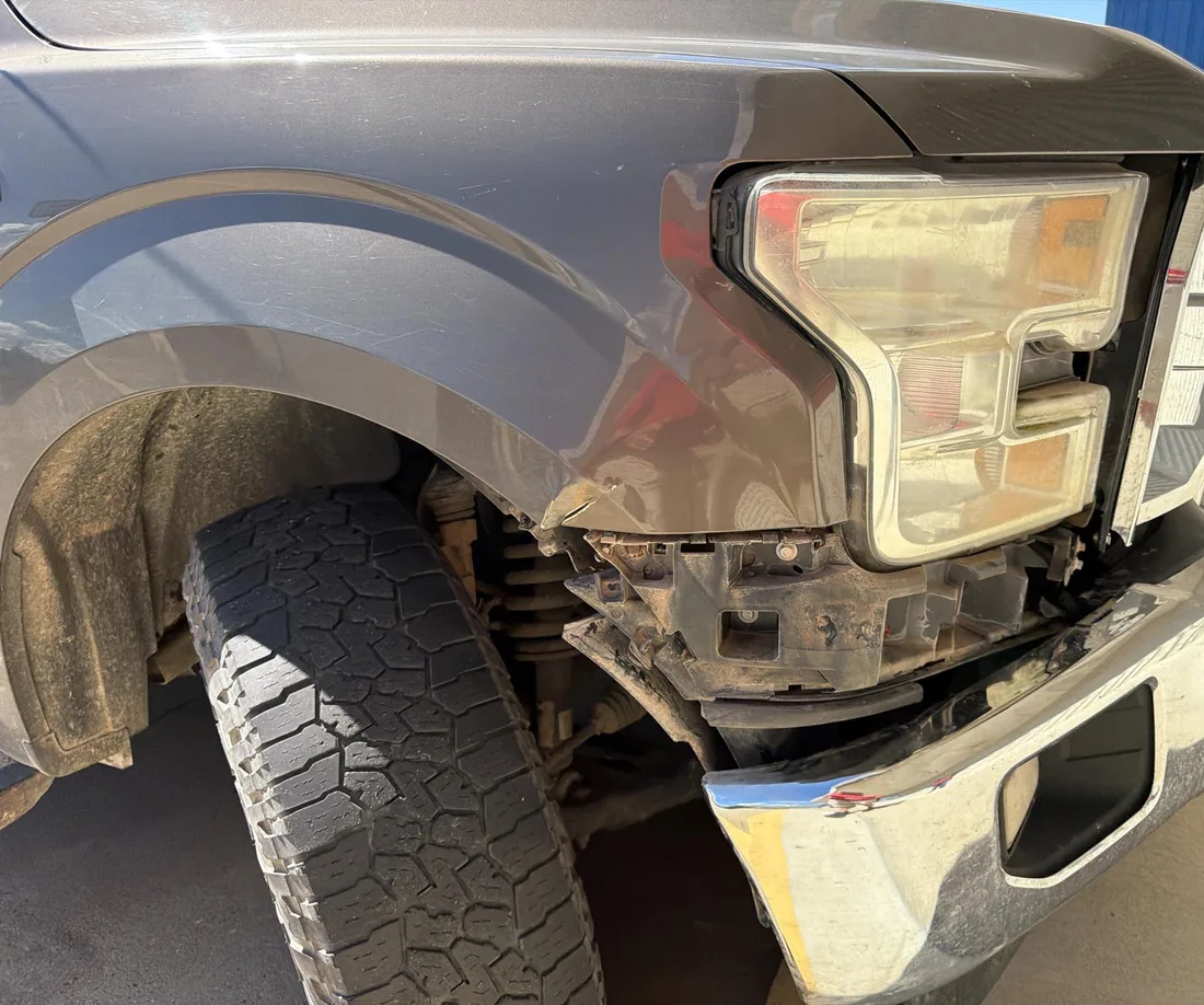 Ford F-150 with a bent front bumper and damaged fender beside the headlight.