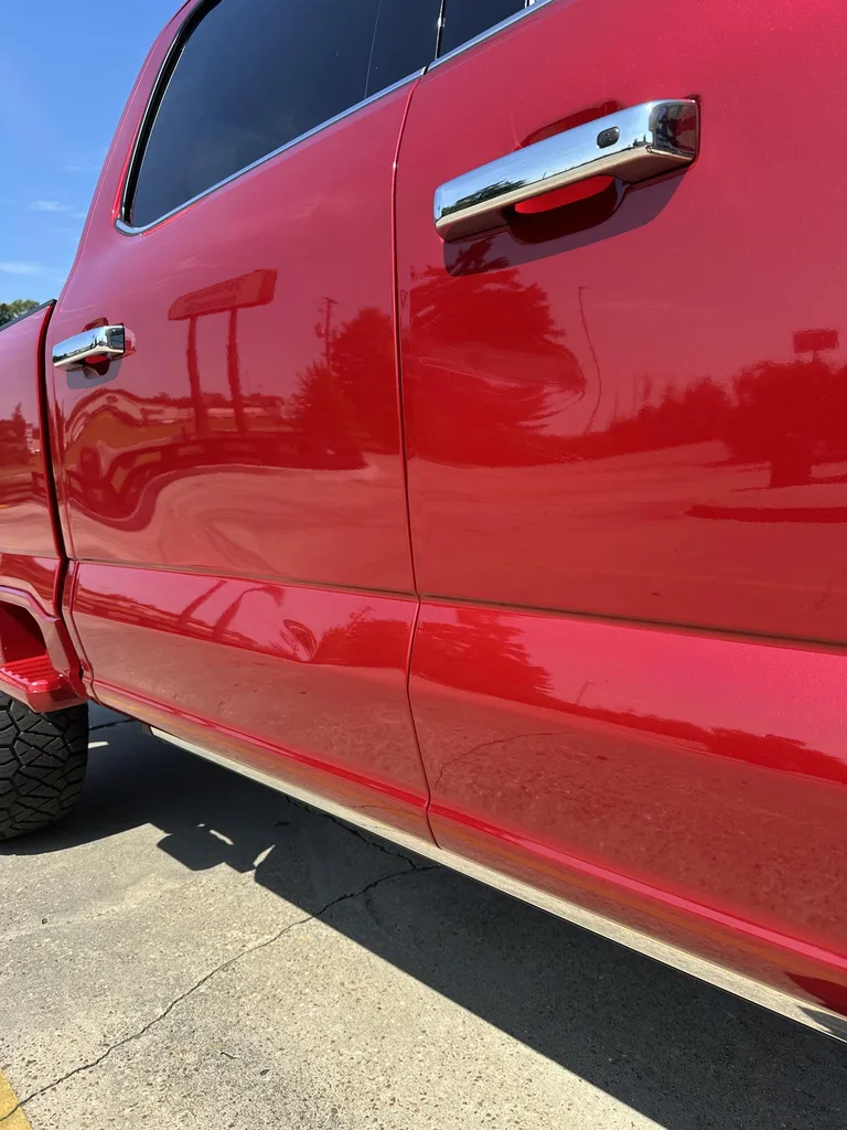 Red Ford F-250 with visible dents and creases across the side doors.